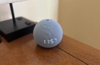 An Echo Dot with LED clock on a wooden table by a lamp